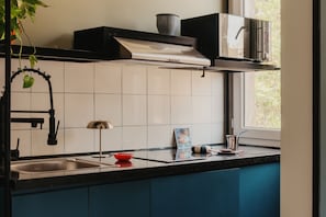 A kitchen with a sink, a microwave, a stove hood, and a window with a view of greenery. - Brassbell Dt Hannaux Tahrir Sq (Cairo)