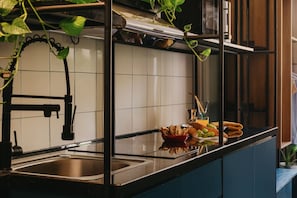Una cocina con un lavamanos de acero inoxidable, grifo negro y una encimera con un bol de aperitivos y un vaso de jugo.
