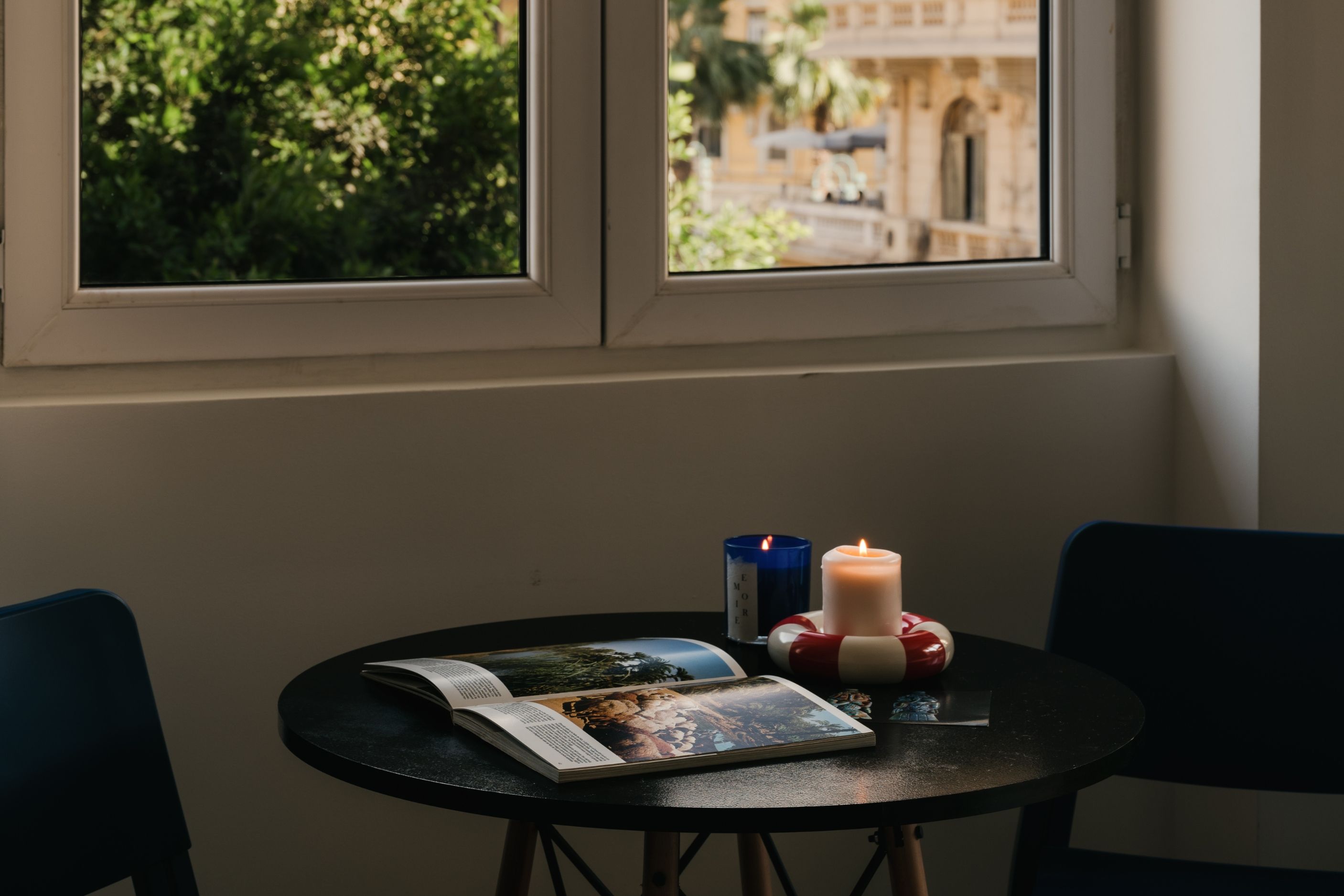 A table with a book, a candle, and a blue container.