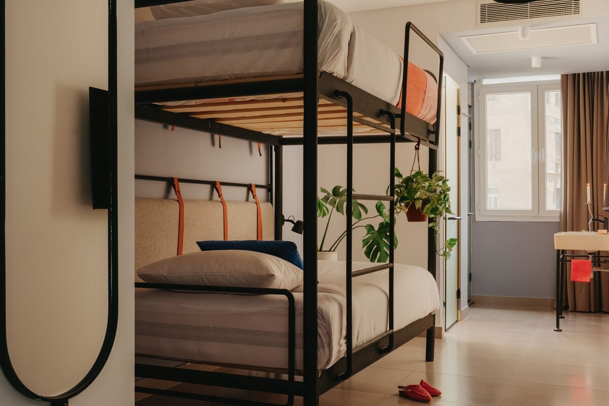 A bunk bed with a desk and a potted plant.