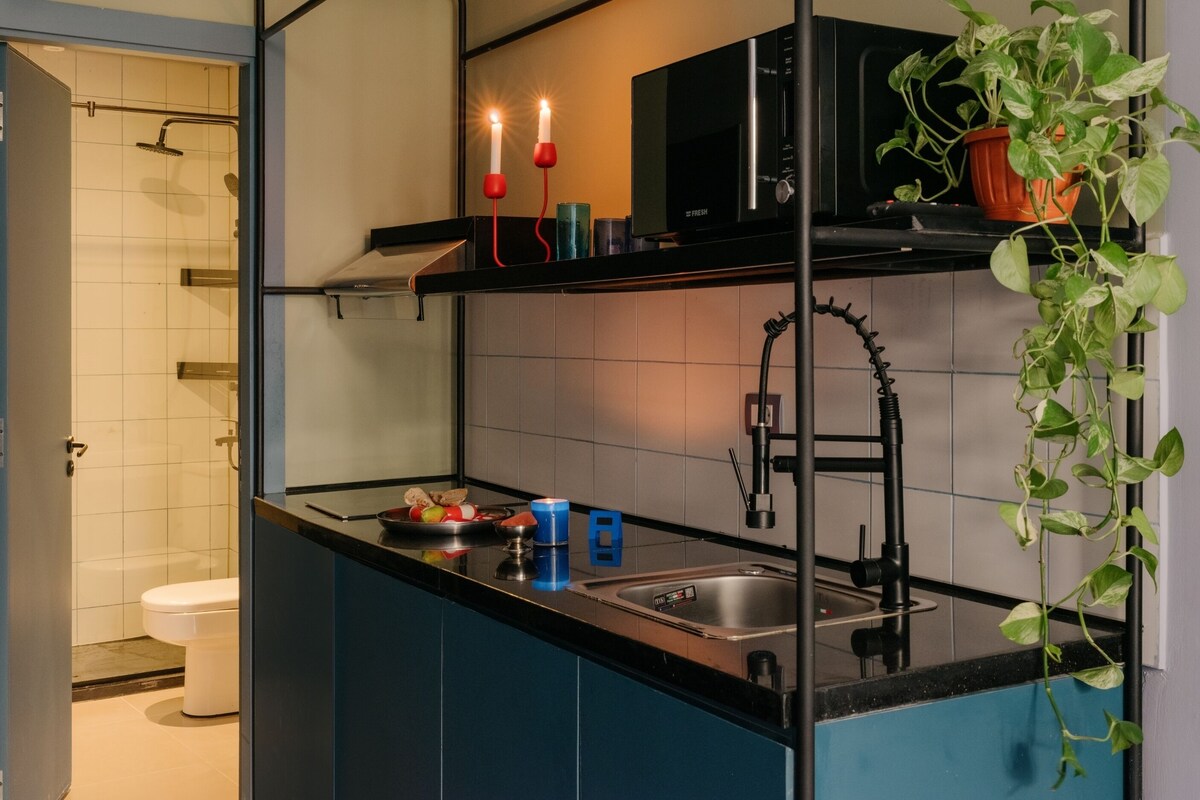 A modern kitchen with a black countertop, stainless steel sink, and a potted plant.