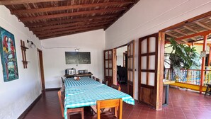 A dining area with a checkered tablecloth, wooden chairs, and a tiled floor. - Kumanday Lodge  (Pereira)