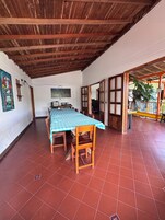 Un comedor con mantel a cuadros, sillas de madera y piso de baldosas.
