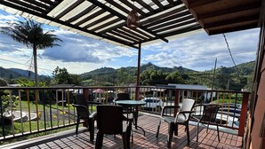 A wooden deck with outdoor furniture, a covered area, and a view of a hilly landscape. - Kumanday Lodge  (Pereira)
