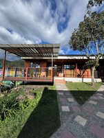 Un edificio con un porche cubierto, un patio de juegos cercado y un árbol en la parte delantera.