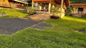 A building with a porch, steps leading to the entrance, and a garden area with plants and a pathway. - Kumanday Lodge  (Pereira)