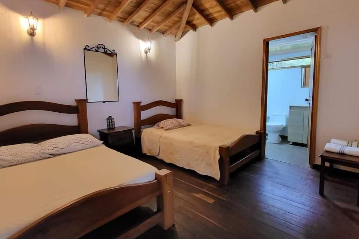 Una habitación con dos camas de madera, techo de madera y un espejo en la pared.