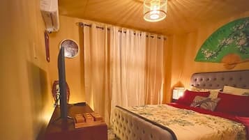 Een slaapkamer met een bed, gordijnen, een lamp en een wandairconditioner.