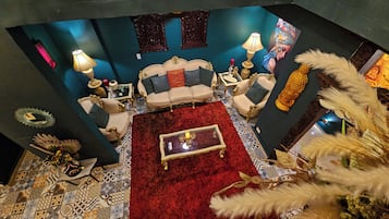 Una habitación con alfombra roja, un sofá, dos sillones, una mesa de centro y una estatua decorativa de Buda.