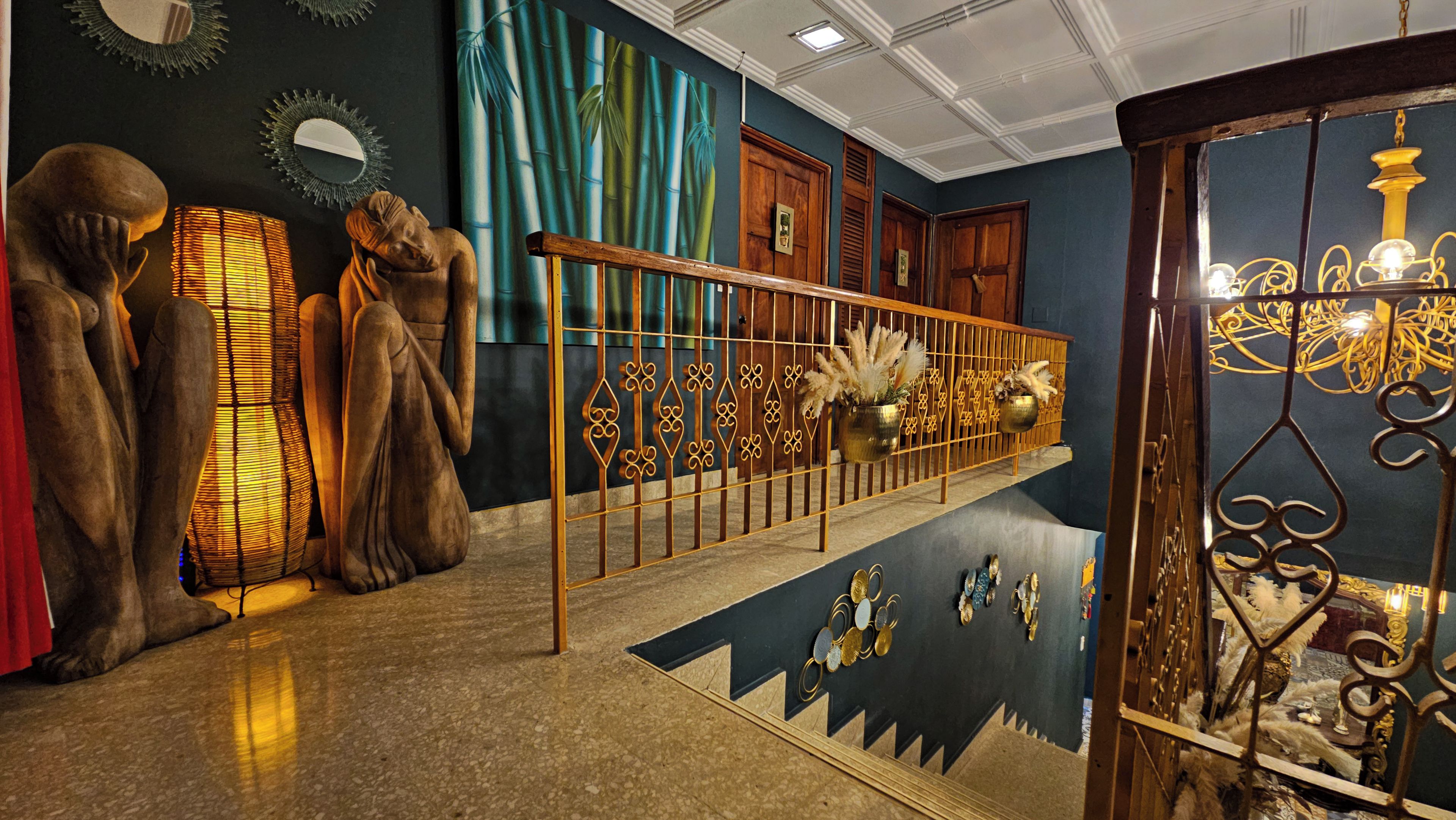 A staircase with a decorative railing, a wall with a bamboo mural, and a series of statues.