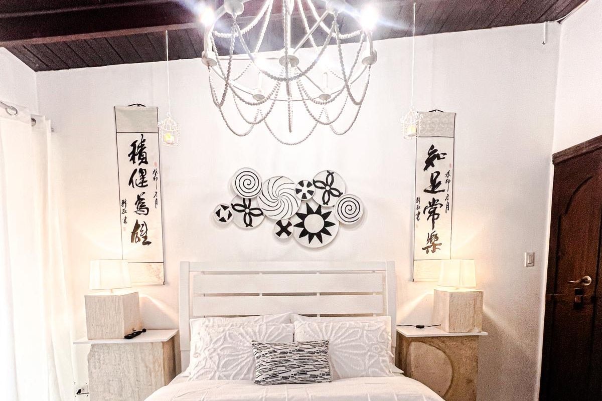 Une chambre à coucher avec un lit, deux tables de chevet avec des lampes, un lustre et des éléments décoratifs sur les murs.