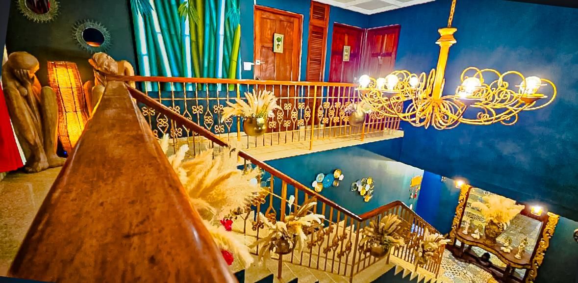 Un interior de varios niveles con una escalera de madera, candelabros y elementos decorativos.