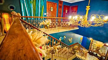 Un interior de varios niveles con una escalera de madera, candelabros y elementos decorativos.