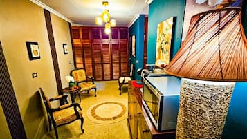 Habitació amb televisió, làmpada, sofà i una catifes amb dibuixos.