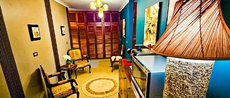 A room with a television, a lamp, a sofa, and a patterned rug.