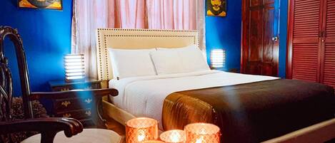 A bedroom with a bed, bedside lamps, a chair, and a bedside table.