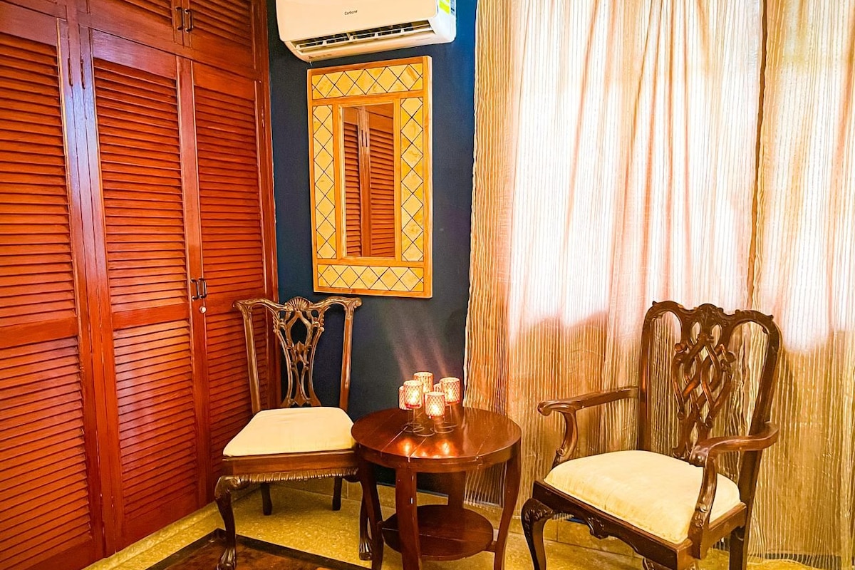 Une pièce comprenant une armoire en bois, une table avec des chaises, un climatiseur fixé au mur et une fenêtre avec des rideaux.