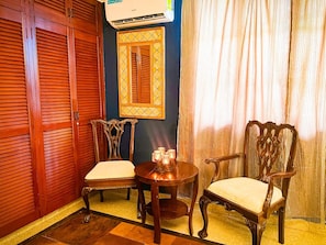 Une pièce comprenant une armoire en bois, une table avec des chaises, un climatiseur fixé au mur et une fenêtre avec des rideaux.