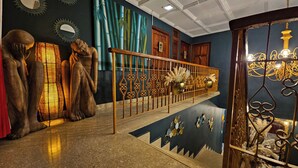 Un escalier agrémenté d’une rampe décorative, un mur orné d’une fresque représentant des bambous et une série de statues.