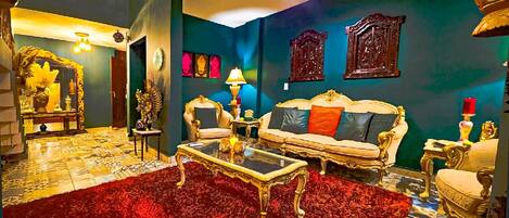 A room with a red carpet, a sofa set, a coffee table, and a decorative mirror.
