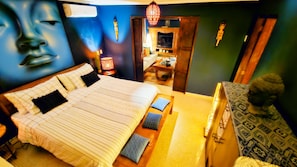 Une chambre à coucher avec un grand lit, une table de chevet, une lampe et une statue.