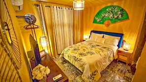 Ein Schlafzimmer mit einem Bett, einem Nachttisch, einem Wandventilator und einer Wanduhr.