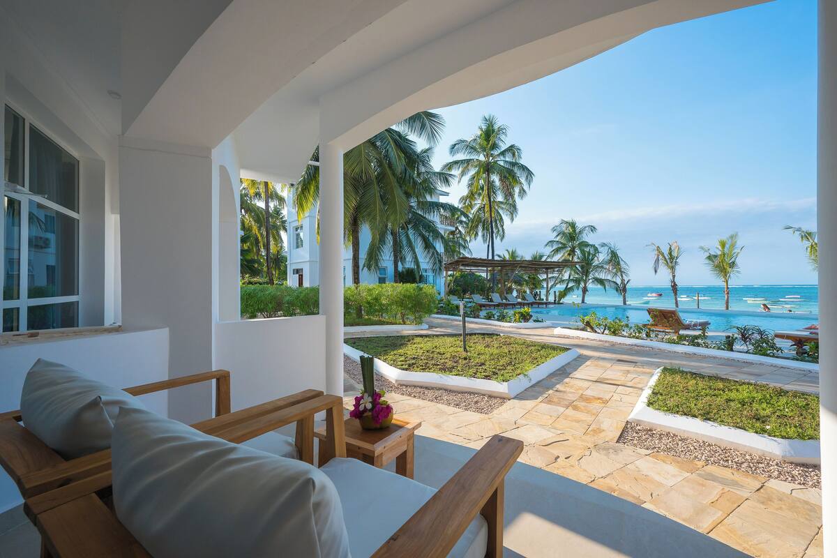 Habitación de hotel con vista a la playa y palmeras.