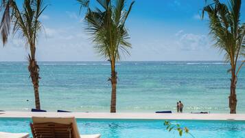 Vista de la piscina con palmeras y una vista despejada del océano.