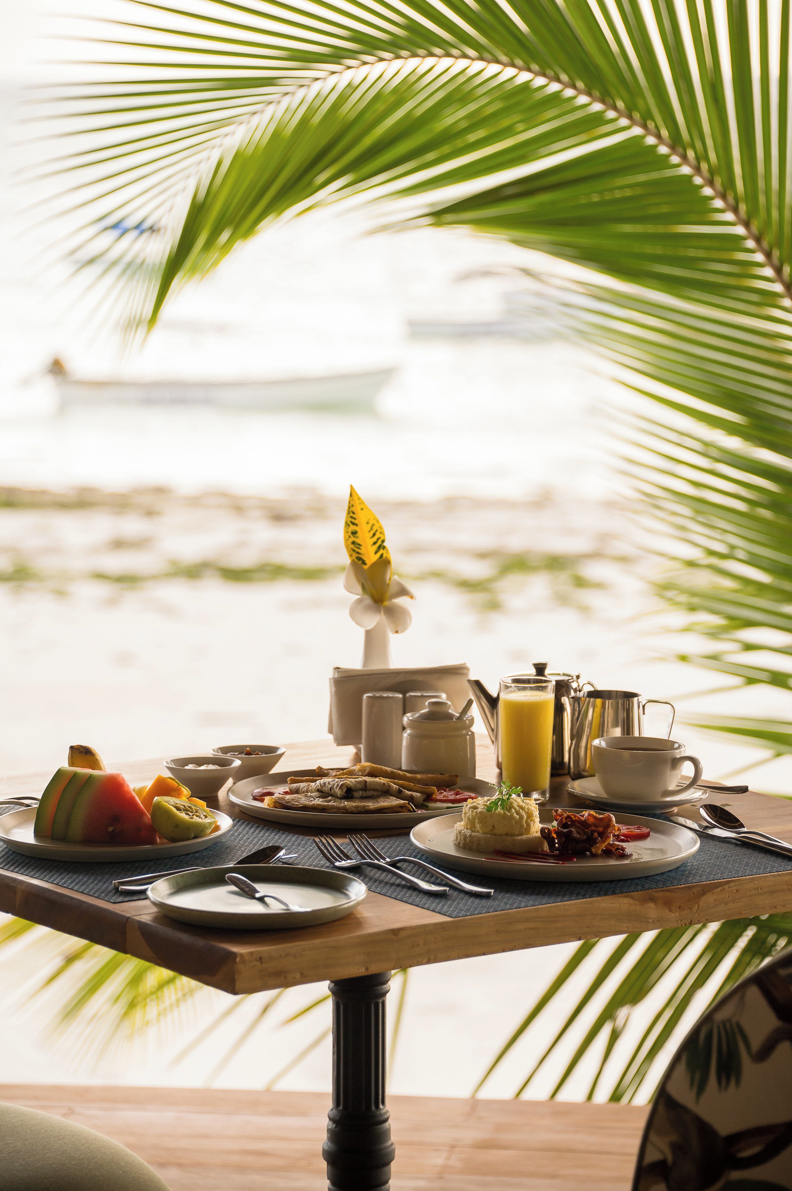 A breakfast table with various dishes and a view of the beach.
