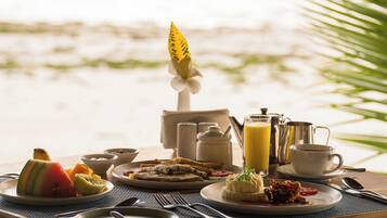 A breakfast table with various dishes and a view of the beach.