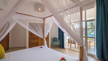 A bedroom with a canopy bed, a view of the pool, and a chair by the window.