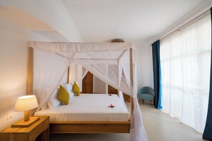 Ein Hotelzimmer mit einem Himmelbett, einem Nachttisch mit Lampe und einem Sessel.