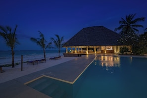 Ein Resort mit Pool, Liegestühlen und einem Gebäude mit Reetdach.
