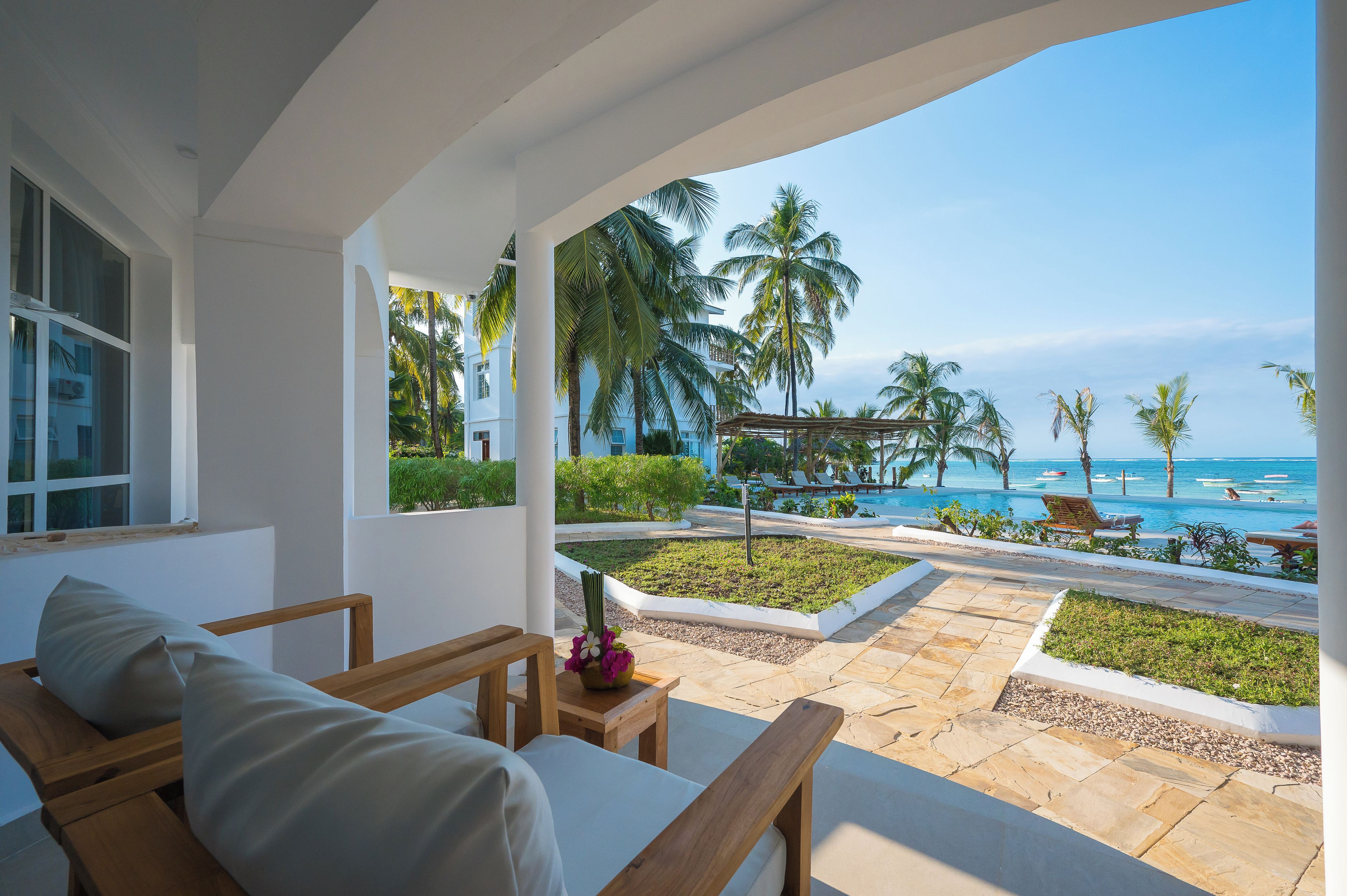 A hotel room with a view of the beach and palm trees.