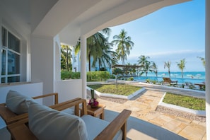 Ein Hotelzimmer mit Blick auf den Strand und Palmen.
