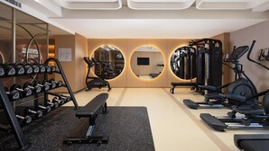 Ein modernes Fitnessstudio mit verschiedenen Trainingsgeräten, darunter Laufbänder, Crosstrainer und Kraftstationen.