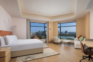 A modern hotel room with a large bed, a desk, a chair, and two windows offering a city view. - Hilton Garden Inn Dongguan Wanjiang Jiangjing Road (Dongguan)