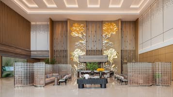 A spacious lobby with a central seating area, a decorative wall with vertical panels, and a modern ceiling design.
