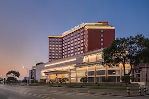 Un hôtel Hilton Garden Inn doté d’une façade rouge bien visible, de plusieurs étages et d’un hall d’entrée bien éclairé.