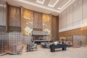Un hall d’entrée moderne doté d’un bar central, de différents espaces aménagés pour s’asseoir et de panneaux muraux décoratifs.