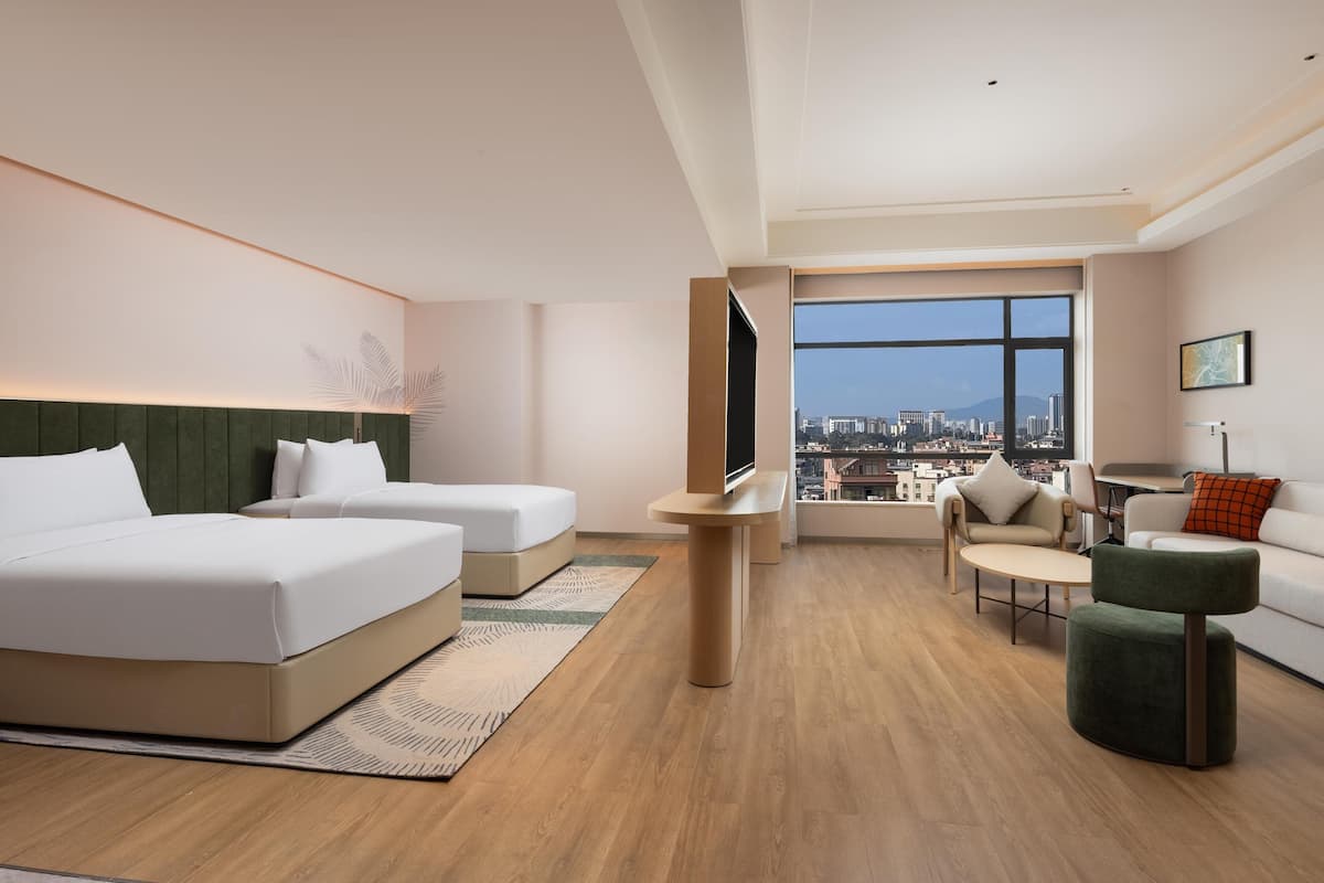 Une chambre d’hôtel moderne avec deux lits, un canapé, une petite table et une vue sur la ville.