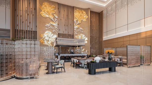 Eine moderne Lobby mit einer zentralen Bar, Sitzgelegenheiten und dekorativen Wandverkleidungen.