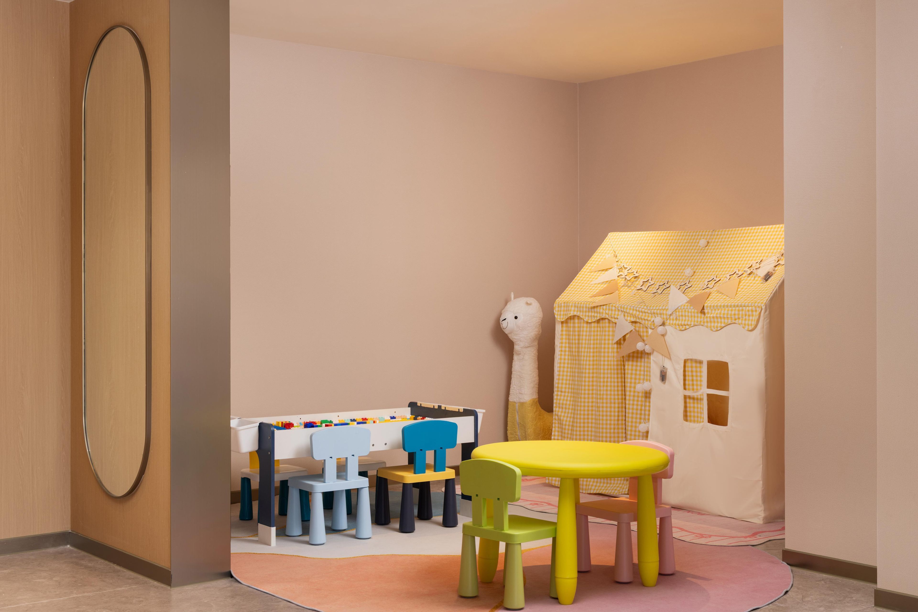 Een speelruimte voor kinderen met een tafel, stoelen en een speelhuis.