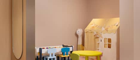 Een speelruimte voor kinderen met een tafel, stoelen en een speelhuis.