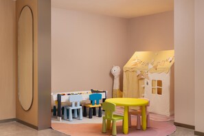 Un espace de jeux pour enfants avec une table, des chaises et une maisonnette.