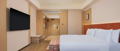 Ein Hotelzimmer mit einem Bett, einem Fernseher, einem kleinen Tisch und einer Bank.