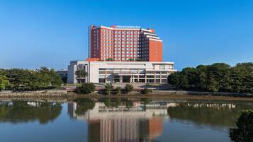 A Hilton Garden Inn hotel with a reflection in the water, surrounded by greenery.