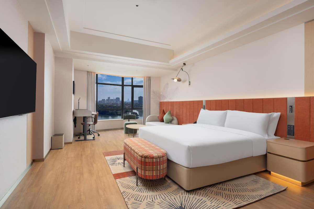 Une chambre d’hôtel moderne dotée d’un grand lit, d’un bureau et offrant une vue sur la ville.