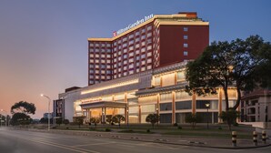Ein Hilton Garden Inn Hotel mit einer auffälligen roten Fassade, mehreren Etagen und einem gut beleuchteten Eingangsbereich.