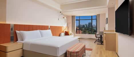 A modern hotel room with a large bed, a desk, a chair, and a TV.